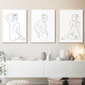 Three Line Art Prints On The Wall Above A White Cabinet In A Modern