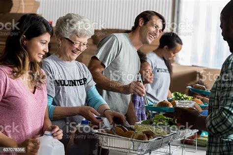 Diverse Group Of Volunteers Serve Meals In Homeless Shelter Stock Photo