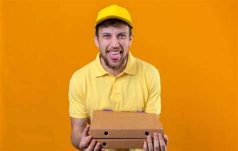 Free Photo Delivery Man In Yellow Polo Shirt And Cap Holding Pizza