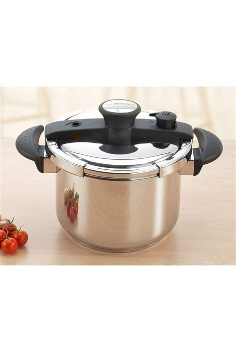 A Stainless Steel Slow Cooker With Lid On A Wooden Table Next To