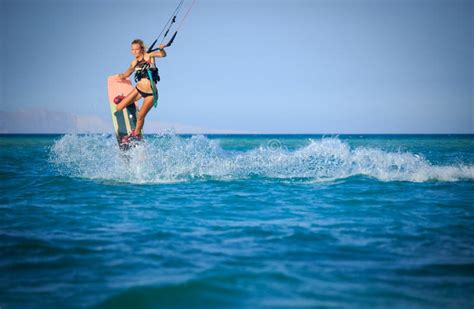 Kite Surfing Girl In Swimsuit With Kite In Sky On Board In Blue Sea