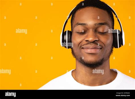 Relaxed Black Guy Listening Music With Eyes Closed Yellow Background