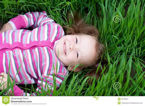 Petite Fille De Sourire Se Trouvant Sur L Herbe Verte Image Stock