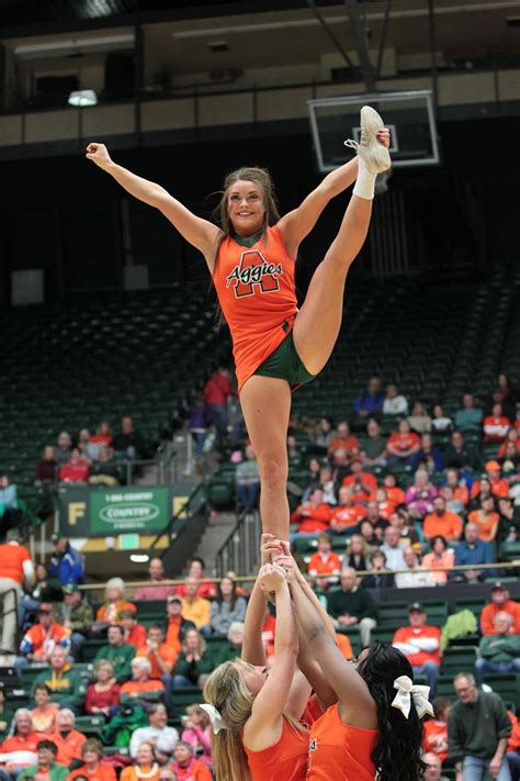 Two Cheerleaders Are Doing Tricks In Front Of An Audience At A Basketball Game