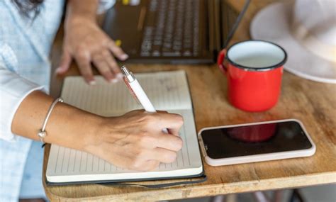 Vista De Cerca De Una Mujer Escribiendo En Un Cuaderno Mientras Trabaja