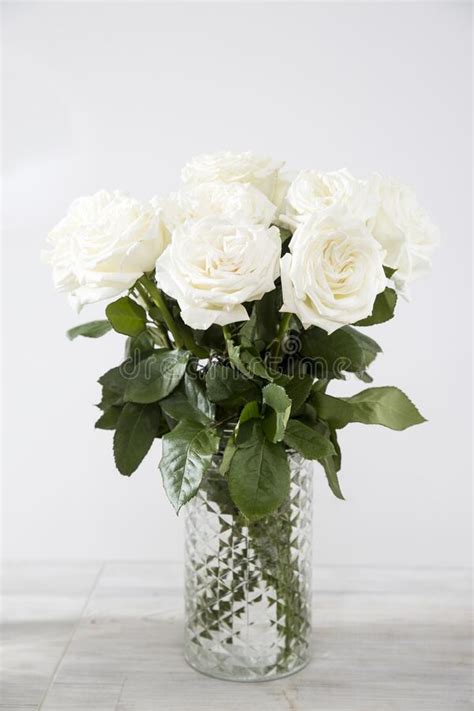 Bouquet Of White Roses In A Glass Vase On A Beige Table Against A Gray