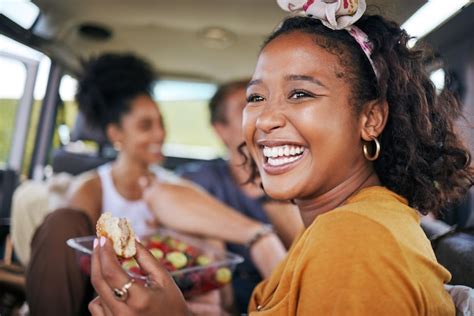 Feliz mujer negra sonríe y come en una aventura de viaje por carretera