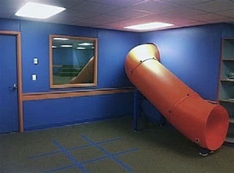 An Orange Slide In The Middle Of A Room With Blue Walls And Carpeted Floors