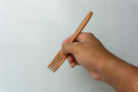 Hand Holding Wooden Spoon And Fork Isolated On White Background