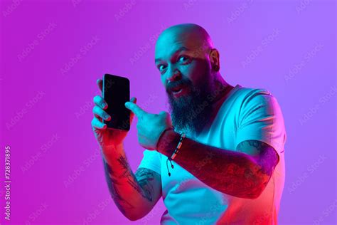 Online Services Bearded Bald Man With Tattoo Pointing On Mobile Phone