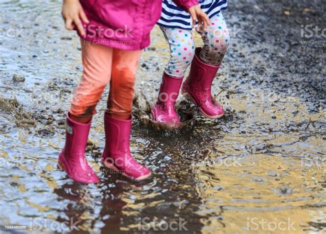 Playful Child Outdoor Jump Into Puddle In Boot After Rain Stock Photo