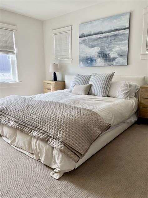 A Large Bed Sitting In A Bedroom Next To Two Windows