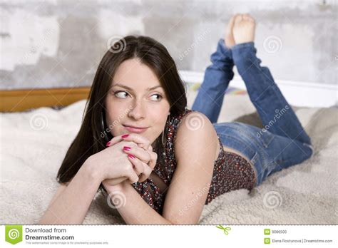 Femme De Sourire Dans Des Jeans Se Trouvant Sur Le Sofa Photo Stock