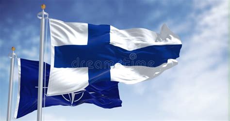 The National Flag Of Finland Waving Along With The Flag Of NATO