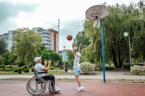 Premium Photo A Man In A Wheelchair Plays Basketball With His Son On