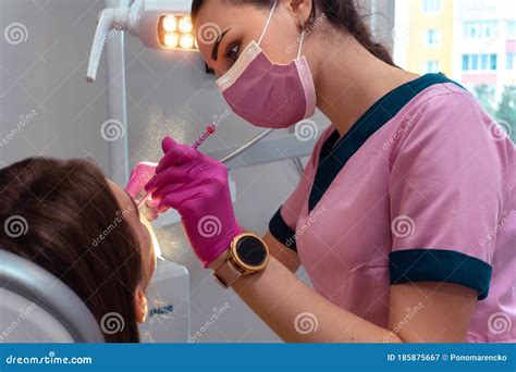 Dentist In Pink Uniform Treat The Teeth Of A Patient Stock Image