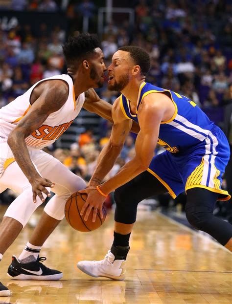 Two Men Playing Basketball On A Court With People Watching From The