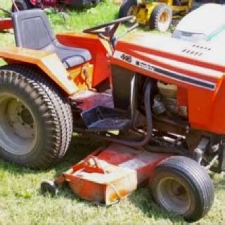 An Orange Lawn Mower Sitting On Top Of A Grass Covered Field Next To