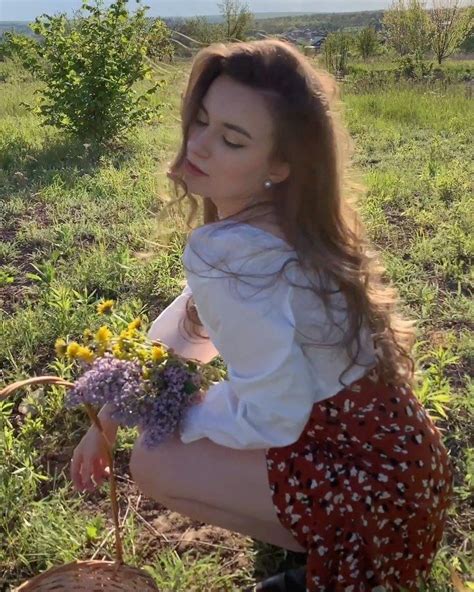 A Woman Kneeling Down In The Grass With Flowers