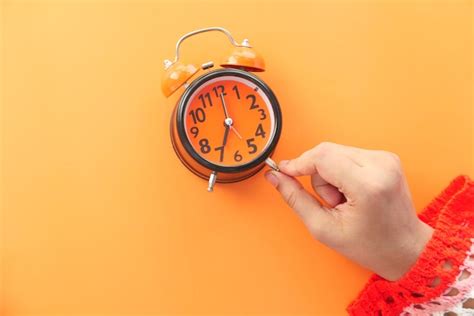 Premium Photo Women Hand Holding Alarm Clock Orange Background