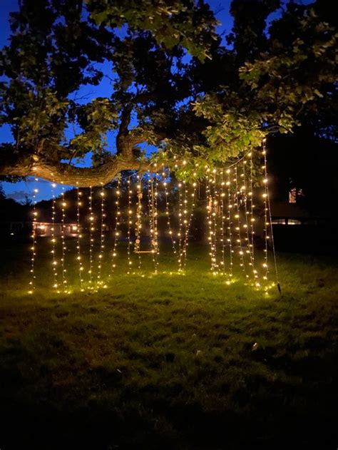 An Outdoor Area With Lights Strung From The Trees And On The Grass At