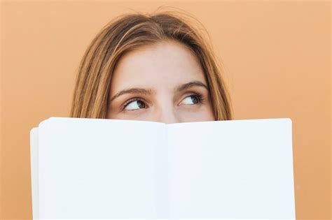 Souriante Jeune Femme Tenant Un Livre Blanc Dans Sa Main En Regardant