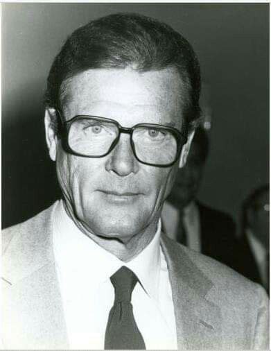 Black And White Photograph Of Man In Suit And Tie Looking At Camera