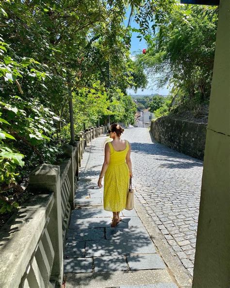 A Woman In A Yellow Dress Is Walking Down The Street