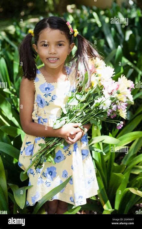 Portrait Of Smiling Girl Holding Flowers Bouquet Standing Amidst Plants