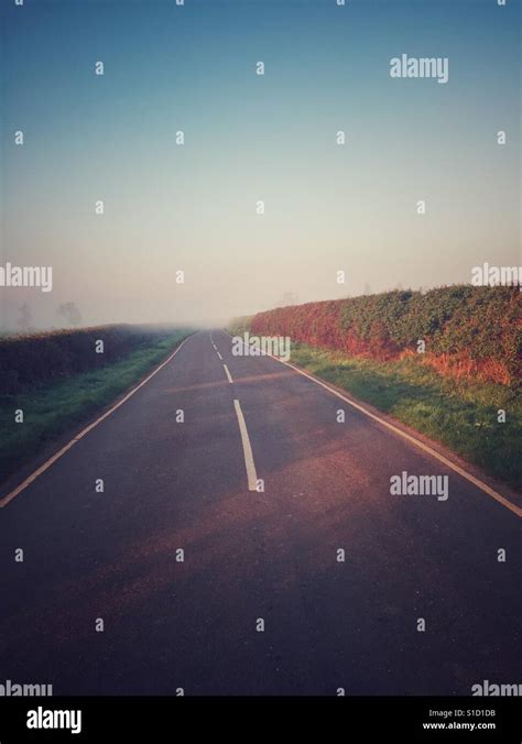 Country Road Disappearing In To Morning Mist Stock Photo Alamy