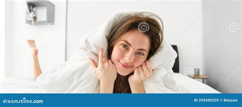 Portrait Of Gorgeous Smiling Woman Lying In Bed Covered In Duvet Has