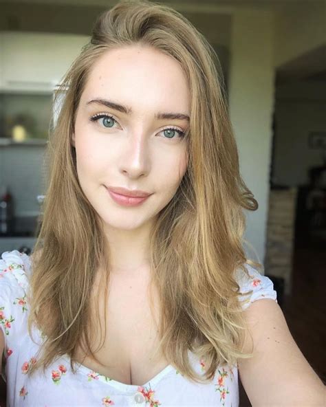 A Woman With Long Hair And Blue Eyes Posing For A Photo In Front Of A Kitchen