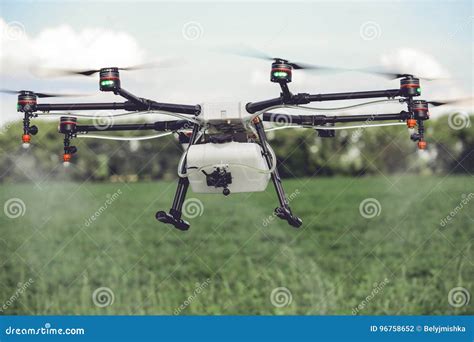 Agriculture Drone Spraying Water Or Pesticides To Grow Over Green Field