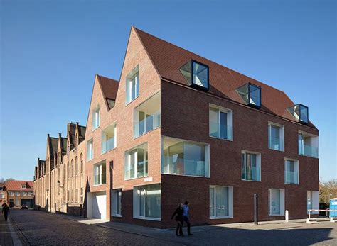 Two People Are Walking On The Sidewalk In Front Of Some Brick Buildings