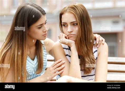 Attractive Girl Comforting Upset Friend While Sitting On Bench Stock