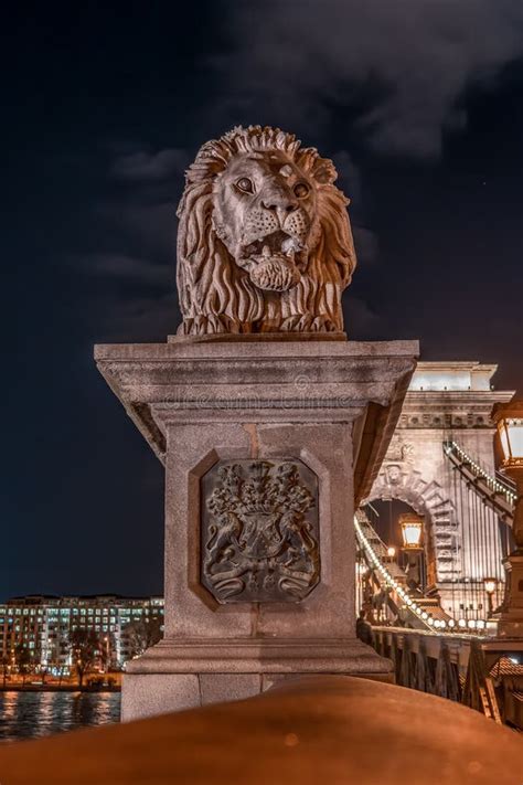 Stone Lion On Szechenyi Chain Bridge With Lights On In Budapest Stock