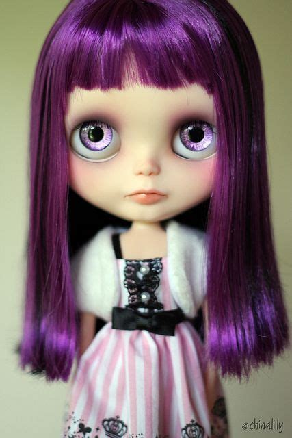 A Close Up Of A Doll With Purple Hair And Big Blue Eyes Wearing A Dress