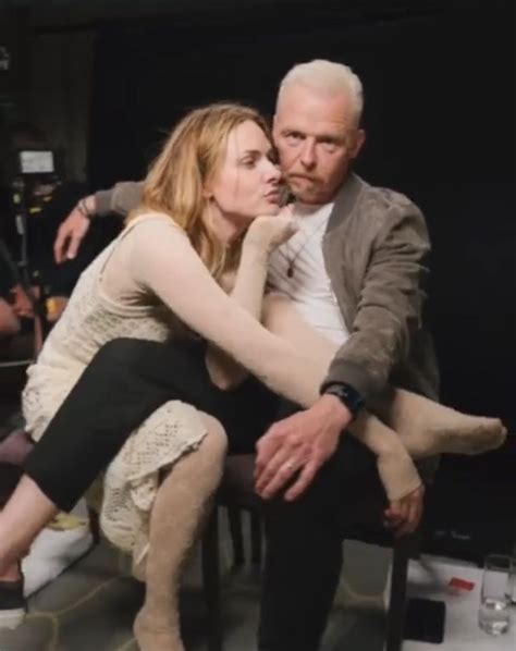 An Older Man Sitting Next To A Woman On Top Of A Chair In Front Of A Camera