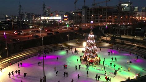 Slow pan of people ice skate around a Christmas tree in a skating rink ...