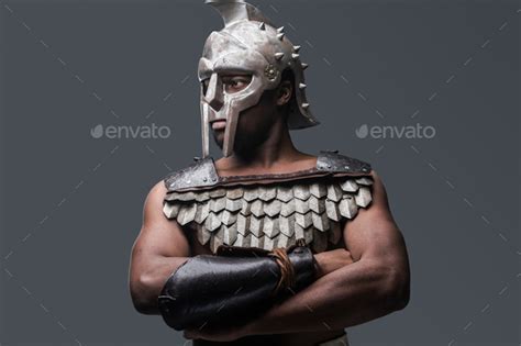 Proud Gladiator Wearing Armor And Helmet On Gray Background Stock Photo