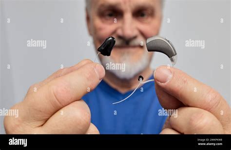 Senior Man With Hearing Problems Chooses Between Behind The Ear Hearing Aid And In The Ear