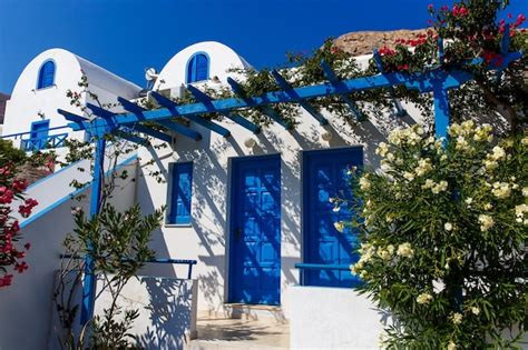 Típica casa griega con puerta azul y planta de buganvillas en flor en