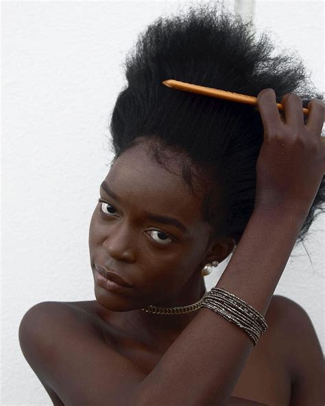 A Woman With An Afro Holding A Pencil Up To Her Hair