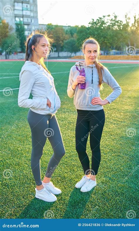 Twee Meisjes In Sportkleding Die In Het Stadion Van Twee Sportvriendinnen Poseren Stock Foto