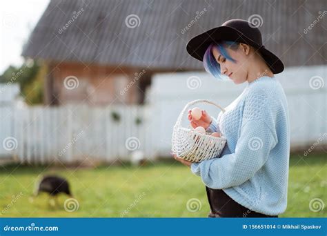 Young Beautiful Girl In A Village Holding A Basket With Chicken Eggs