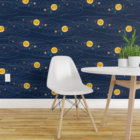 two white chairs sitting at a table in front of a wall with planets on it