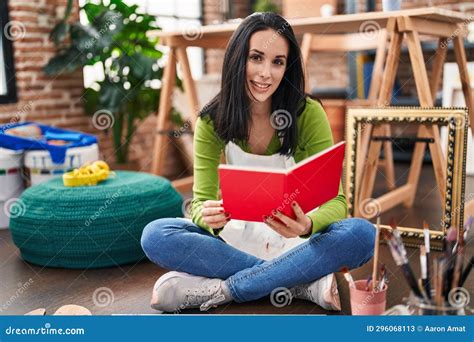 Young Caucasian Woman Artist Sitting On Floor Reading Book At Art