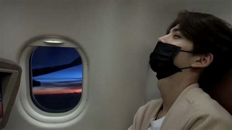 A Woman Wearing A Face Mask Looking Out An Airplane Window