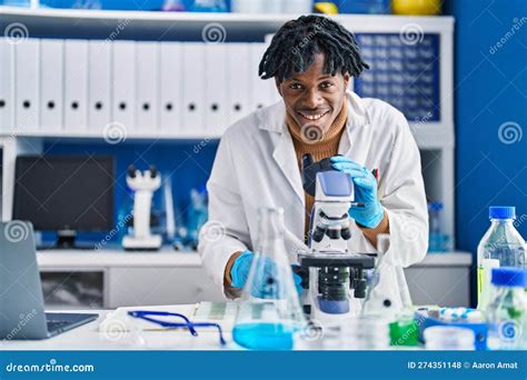 African American Man Scientist Using Microscope At Laboratory Stock