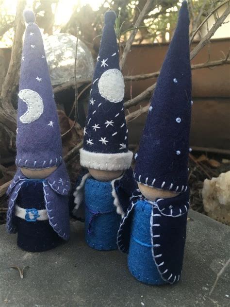 Three Gnomes Made Out Of Felt Sitting On Top Of A Cement Slab In Front